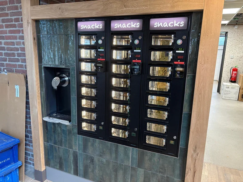 Zwarte ADM-automaten met paarse tekstplaten en de tekst snacks in witte lettering