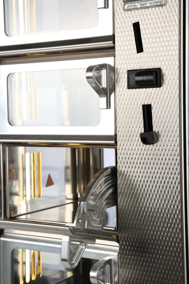 Het open RVS-loket en scharnier van een ADM snackautomaat in detail