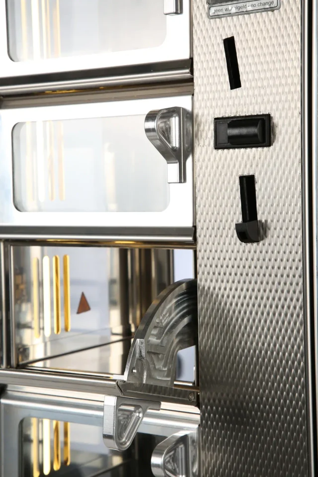 Close-up van het uitgifteluik en scharnier van een ADM-automaat